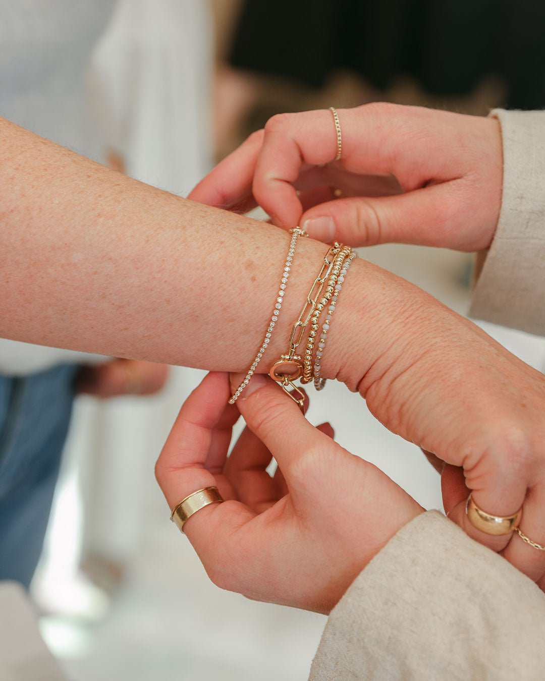 retail associate helping a customer put on a bracelet